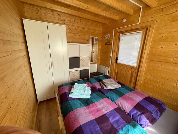 A wooden-paneled room with a bed, a wardrobe, a radiator, and a window.