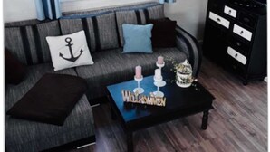 Un salon avec un canapé, une table basse, un téléviseur et une fenêtre avec des rideaux.