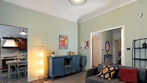 A living room with a sofa, a dining table with chairs, a kitchen area with a stove, and a blue cabinet.