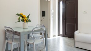 A dining area with a table, chairs, and a vase of flowers. There is a door and a light switch on the wall. - Villetta Silvana by Wonderful Italy (Ostuni)