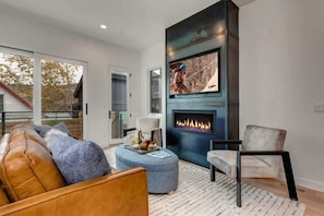 A modern living room with a fireplace, a sofa, a chair, and a coffee table.
