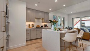 A modern kitchen with a central island, bar stools, and a large window. - Abode on Cloud 9, private hot tub, Old Town retreat, groups (Park City)