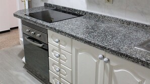 A kitchen with white cabinets, a granite countertop, and a built-in oven.