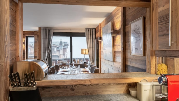 A wooden interior with a dining area, kitchen counter, and coffee machine.