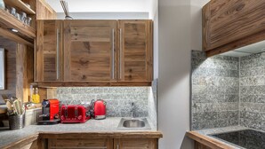 A kitchen with wooden cabinets, a granite countertop, a red toaster, a kettle, and a sink.