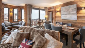 A cozy, wood-paneled room with a sofa, dining table, and chairs.