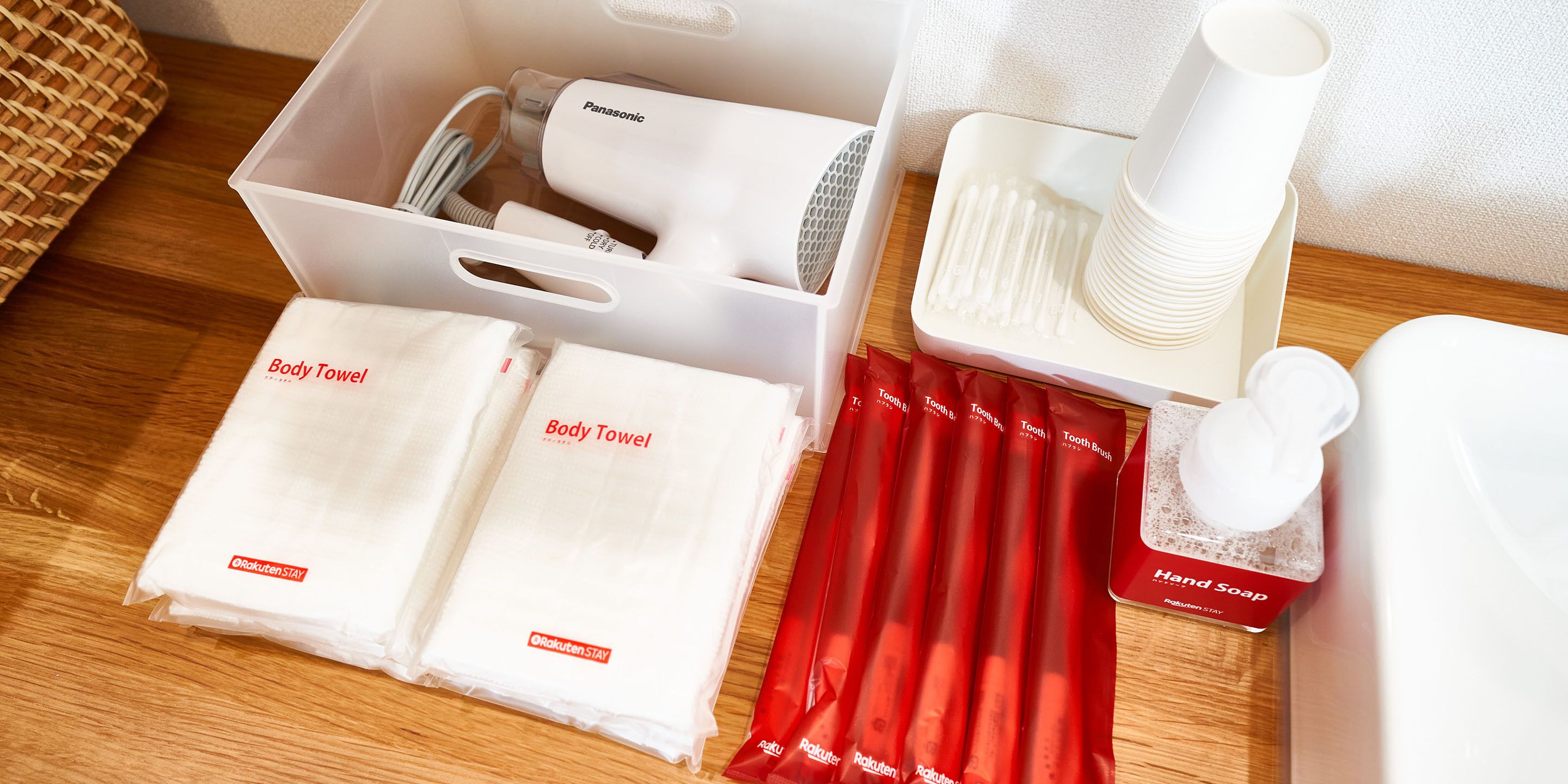 A neatly arranged set of toiletries including body towels, a hairdryer, toothbrushes, and a hand soap dispenser.