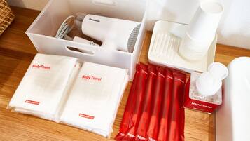 A neatly arranged set of toiletries including body towels, a hairdryer, toothbrushes, and a hand soap dispenser.