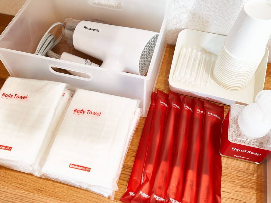 A neatly arranged set of toiletries including body towels, a hairdryer, toothbrushes, and a hand soap dispenser.