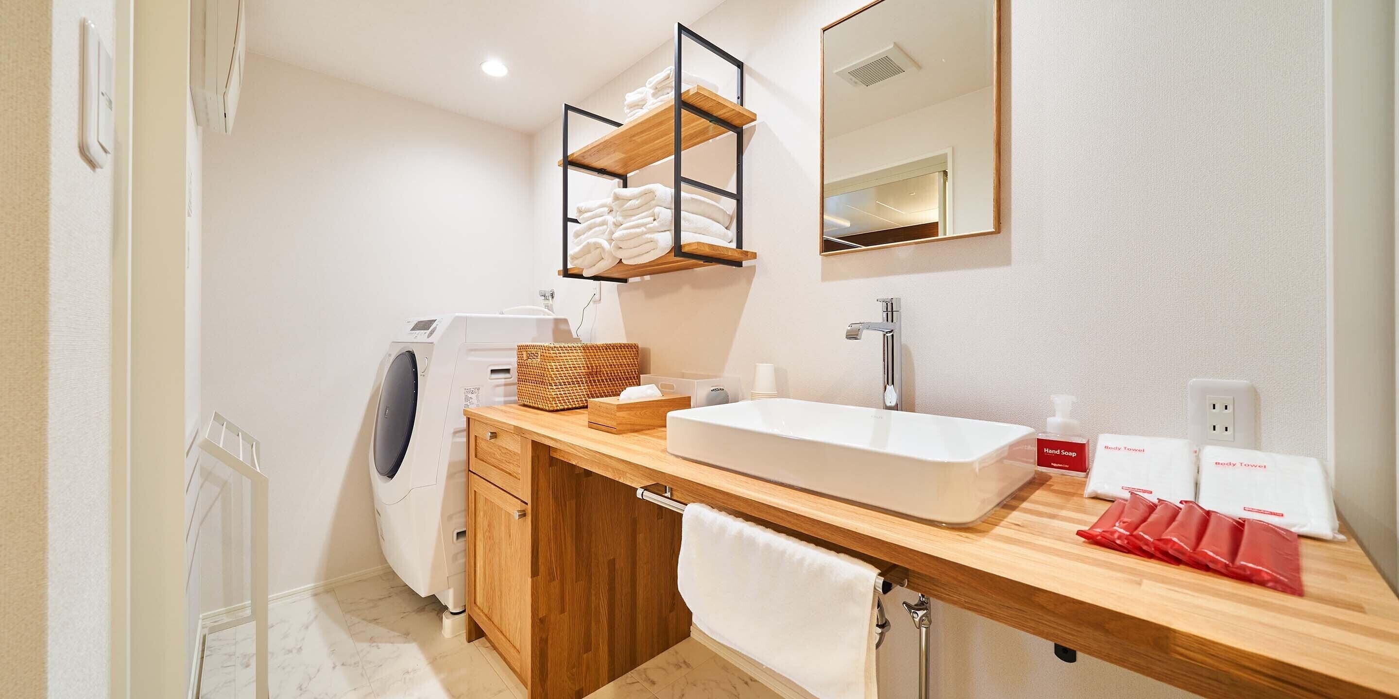 A modern bathroom with a built-in washing machine, a large sink, and a mirror above it.