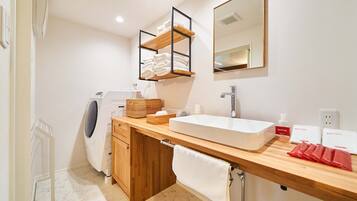 A modern bathroom with a built-in washing machine, a large sink, and a mirror above it.
