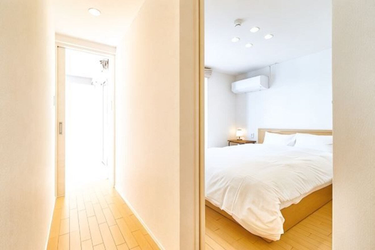 A bedroom with a bed, a bedside table, and a wall-mounted air conditioner.