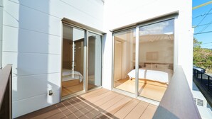 A modern bedroom with a large sliding glass door, a wooden deck, and a view of the surrounding area. - Rakuten STAY HOUSE WILL STYLE Saga Imari (Imari)