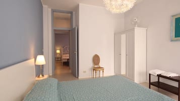 Camera da letto con un letto, una sedia, un armadio, un comodino, una lampada e un lampadario.