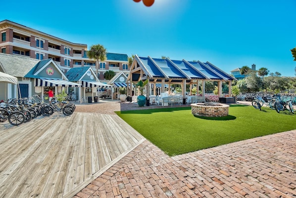 A beachfront hotel with multiple-story buildings, outdoor seating areas, and a bike parking area.