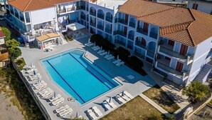 A hotel with a swimming pool, sun loungers, and a courtyard. - Eleana Hotel by GHH (Zakynthos)
