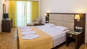 A hotel room with a bed, a desk, a chair, a TV, and a lamp. - Eleana Hotel by GHH (Zakynthos)