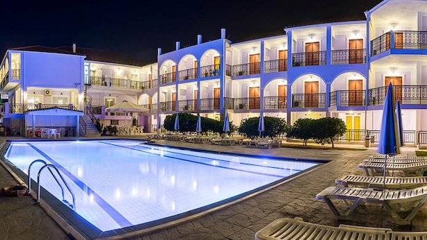 A multi-story hotel with a swimming pool, outdoor seating, and a well-lit facade. - Eleana Hotel by GHH (Zakynthos)