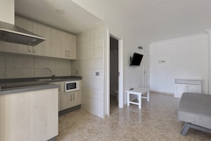 Une cuisine moderne équipée d’un four à micro-ondes, d’un évier et de placards. Une petite table et un banc se trouvent dans la pièce adjacente.