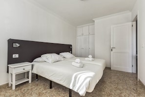 Une chambre à coucher avec un lit, une table de chevet, une armoire et une porte.