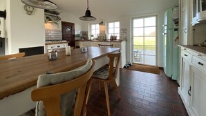 Un'ampia cucina con isola centrale, sedie in legno e illuminazione a sospensione.