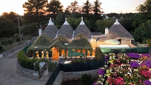 A row of conical-roofed buildings with a stone pathway leading to a flower garden.