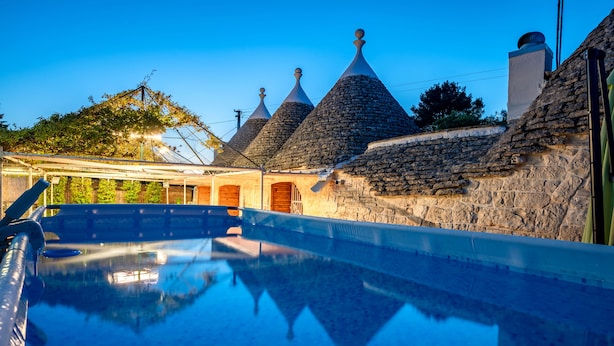 A swimming pool with stone-roofed buildings in the background.