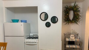 Cocina compacta con refrigerador blanco, estufa y una pequeña mesa de comedor.