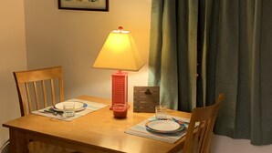 Una mesa de comedor con sillas, una lámpara y un cuadro en la pared.