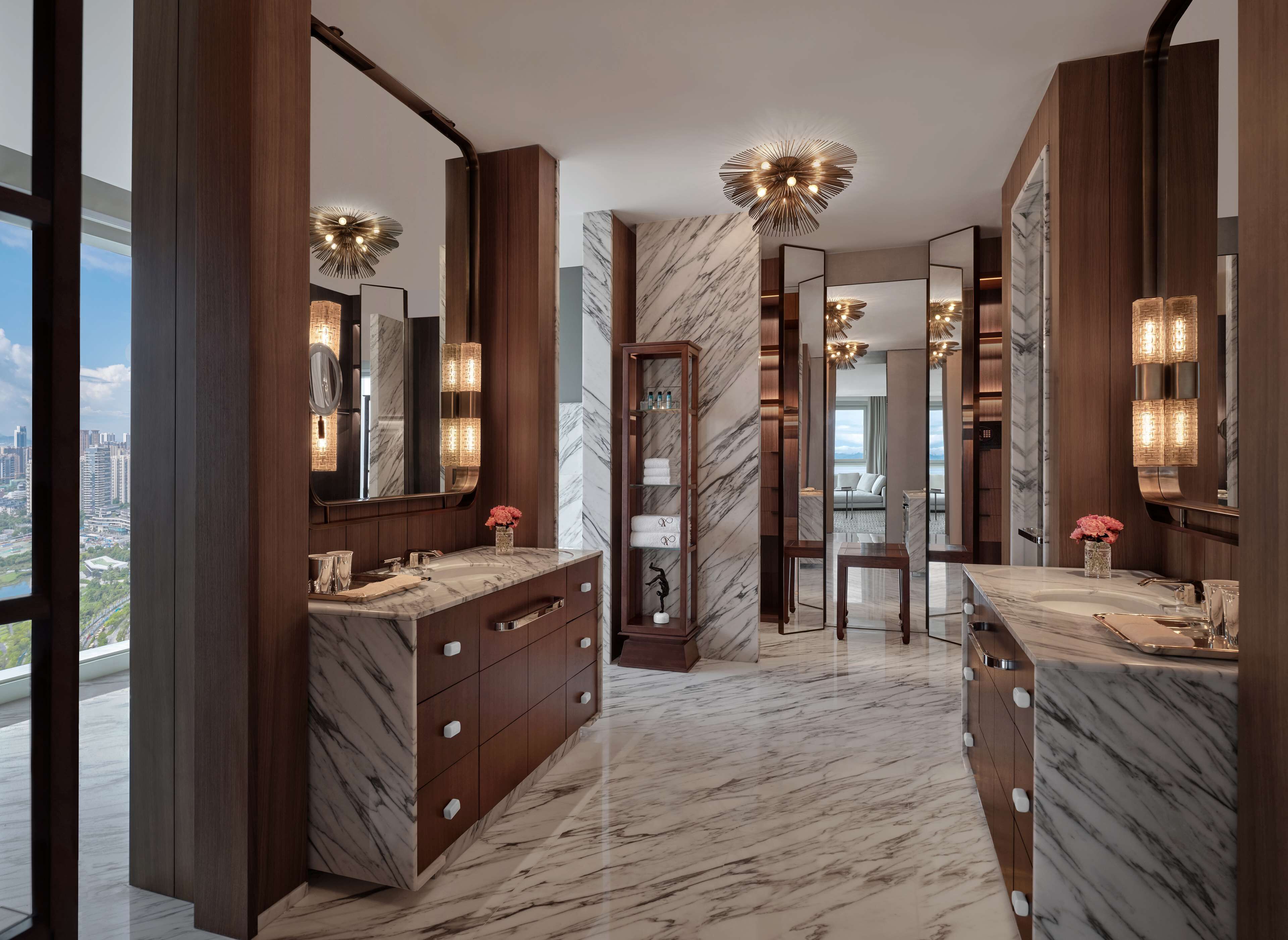 Une salle de bain moderne avec des comptoirs en marbre, des meubles en bois et de grands miroirs.