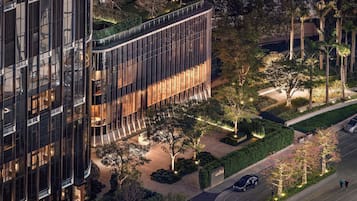 A modern building with a glass facade, surrounded by landscaped gardens and trees.