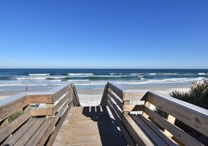 A wooden boardwalk leading to a beach with waves crashing onto the shore.