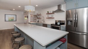 Una cocina moderna con una isla central, electrodomésticos de acero inoxidable y taburetes de bar.