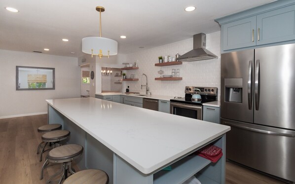 A modern kitchen with a central island, stainless steel appliances, and bar stools.
