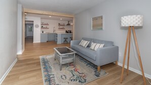 Una sala moderna con un sofá gris, un tapete estampado y una lámpara de pie.