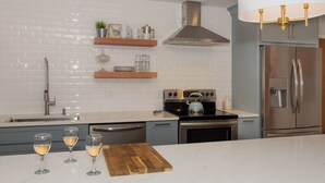 Una cocina moderna con azulejos blancos tipo metro, electrodomésticos de acero inoxidable y estantes de madera.