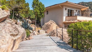 A wooden pathway leading to a building with a tiled roof and a balcony. - Villa Elsa Di Palombaggia (Porto-Vecchio)