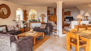 A spacious living area with a sofa, coffee table, and dining table. There is a TV in the background and a window with plants. - Villa Elsa Di Palombaggia (Porto-Vecchio)