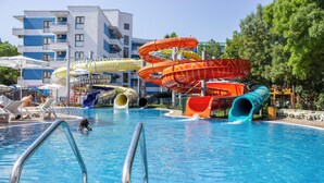 Une piscine dotée de plusieurs toboggans et de chaises longues.