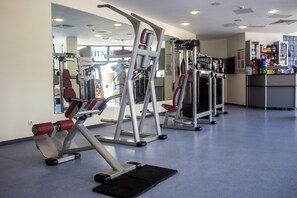 Un gimnasio con equipo de ejercicio, un espejo y un mostrador con bebidas.