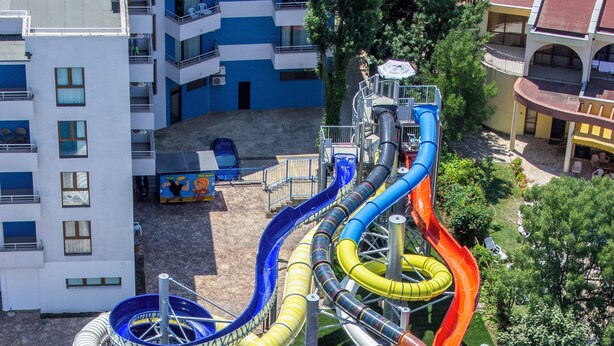 A water park with multiple slides and pools, surrounded by lounge chairs and umbrellas. - Kuban Resort and Aquapark (Nessebar)