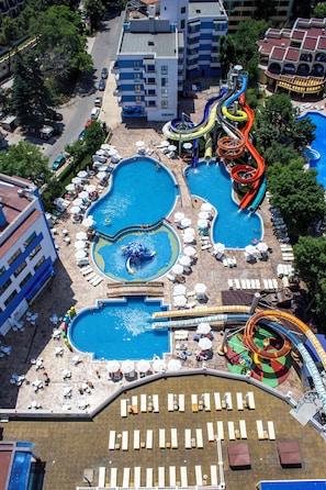 Een resort met meerdere zwembaden, een glijbaan en ligbedden.