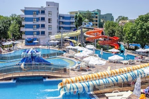 Un parque acuático con múltiples toboganes y piscinas, rodeado de sillas de descanso y sombrillas.