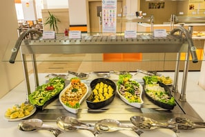 A buffet with various food options and utensils.