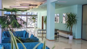 A spacious lobby with a blue sofa, potted plants, and a bench. - Kuban Resort and Aquapark (Nessebar)