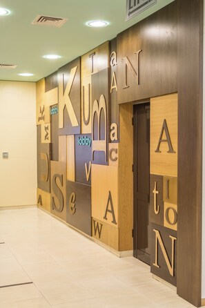 Un vestíbulo con una pared que muestra letras grandes que deletrean 'KUMAN' y un letrero que dice 'lobby'.