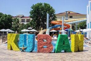 Un parque acuático con letras grandes y coloridas que deletrean 'KUBANA' y una estructura de toboganes al fondo.