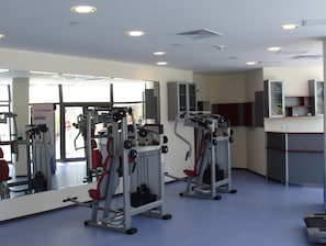 A gym with exercise equipment, a large mirror, and a view of the outside.