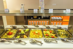 A buffet with various food options, serving utensils, and condiment dispensers.