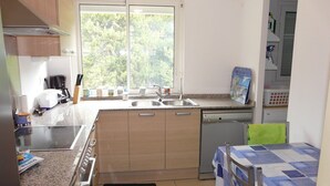 Una cocina compacta equipada con lavavajillas, cafetera y ventana que proporciona luz natural.